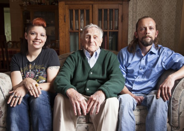 Caucasian couple and older man smiling on sofa