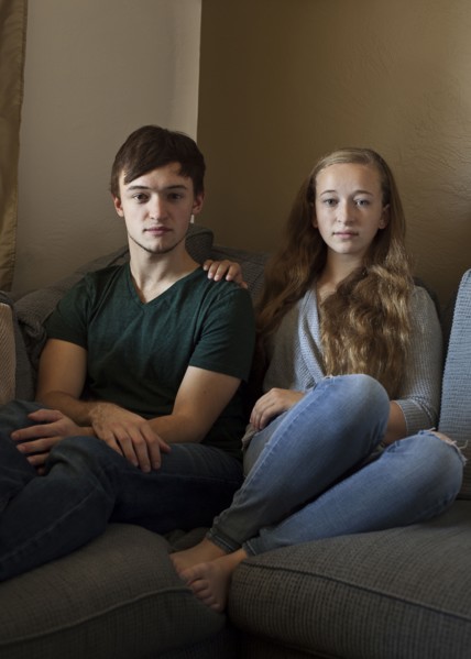 Caucasian brother and sister smiling on sofa