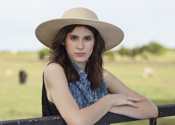 Caucasian woman leaning on fence in rural pasture
