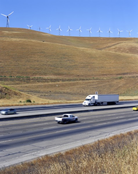Cars and trucks driving on freeway near wind farm