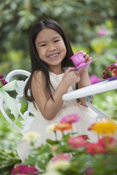 Mixed race girl having tea party in backyard