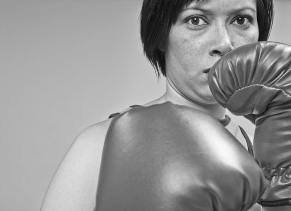 Mixed race boxer holding gloves in front of face