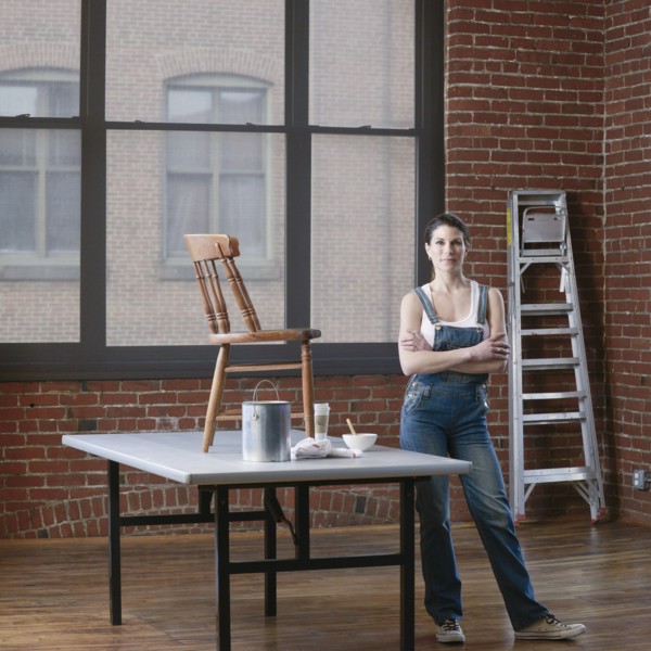 Mixed race woman painting chair in loft