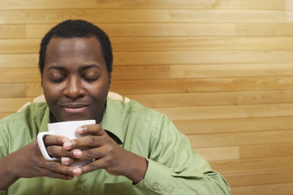African man smelling cup of coffee