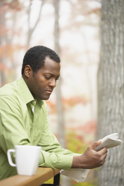 African man reading newspaper outdoors