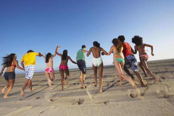 Multi-ethnic group of friends running on beach