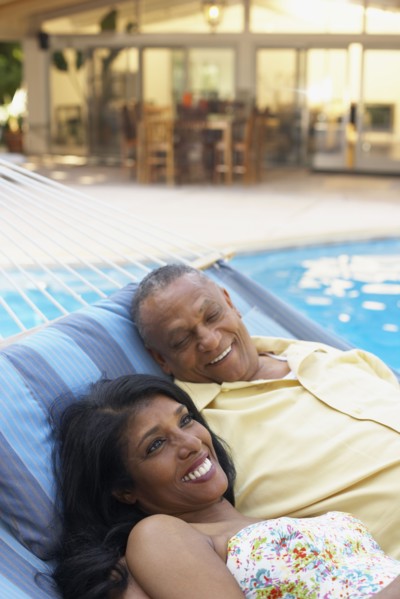Multi-ethnic couple laying in hammock at poolside
