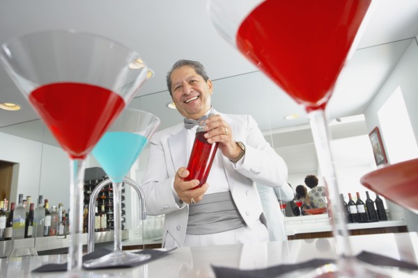 Hispanic host mixing martini cocktails at party