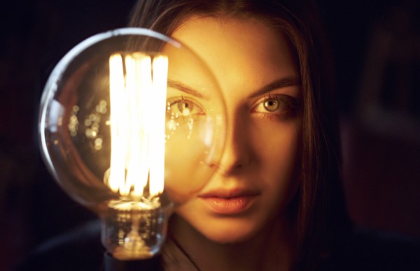 Face of Caucasian woman illuminated by energy efficient light bulb