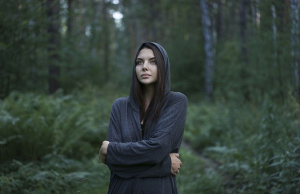 Cold Caucasian woman standing in forest
