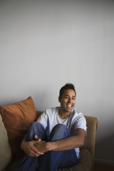 Mixed man sitting on sofa laughing