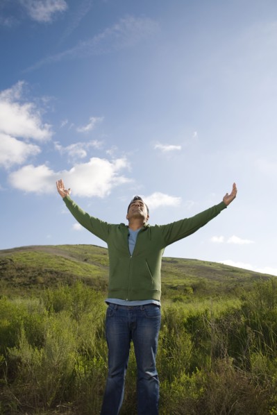 Mixed race man in field with arms outstretched