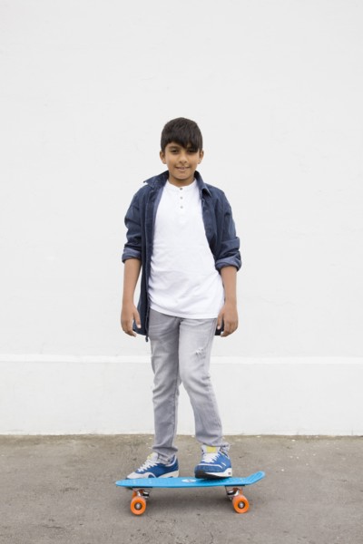 Asian boy standing on skateboard