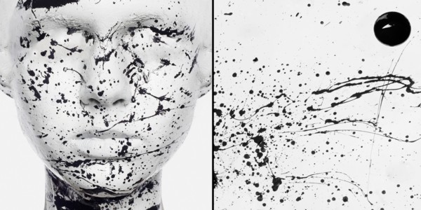 Caucasian woman in white makeup splashed with black paint