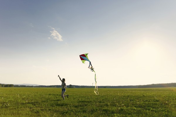 Caucasian girl running in field flying kite