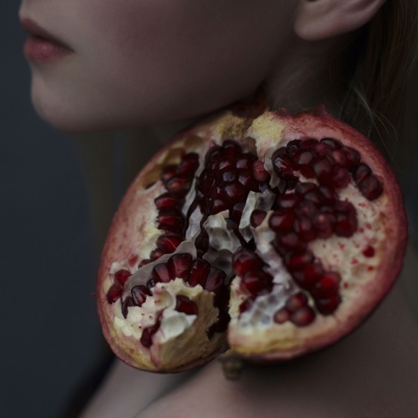 Caucasian girl balancing pomegranate slice on shoulder