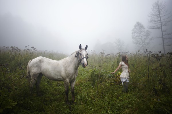 Caucasian girl walking horse in foggy field