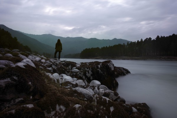 Caucasian girl standing on rocks over foggy river
