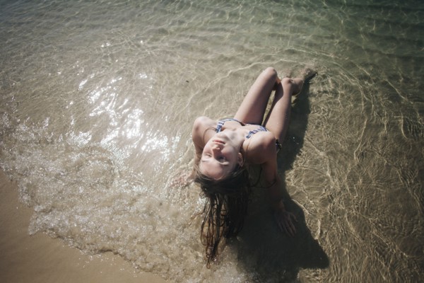 Caucasian woman wearing bikini sitting in waves on beach