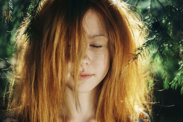 Close up of Caucasian teenage girl near pine tree