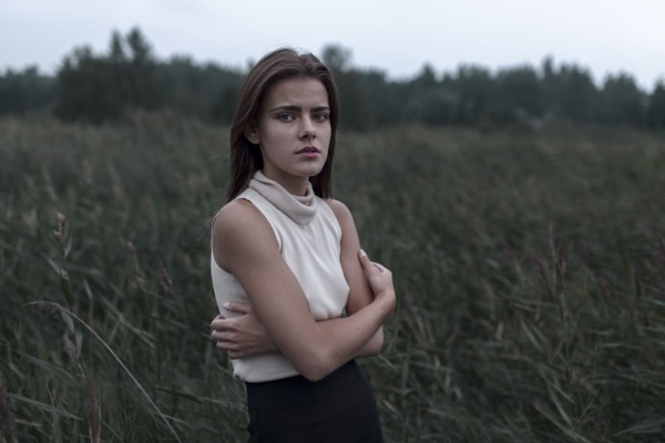Caucasian teenage girl standing in field worrying