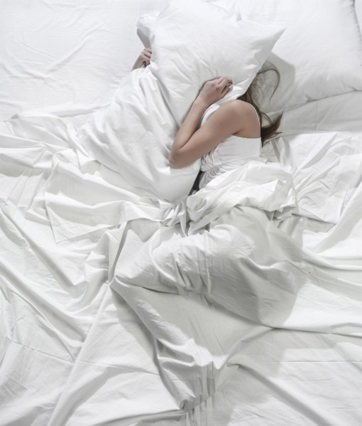 Hispanic woman burying head under pillow