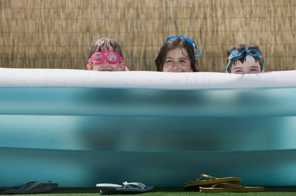 Smiling Caucasian children hiding in inflatable swimming pool