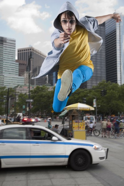 Caucasian man jumping over police car in city