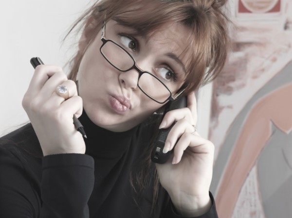 Caucasian businesswoman talking on telephone making a face
