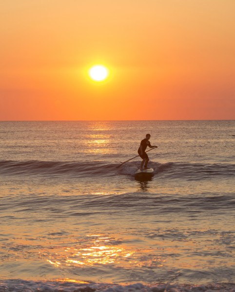 Silhouette of man paddleboarding on ocean waves