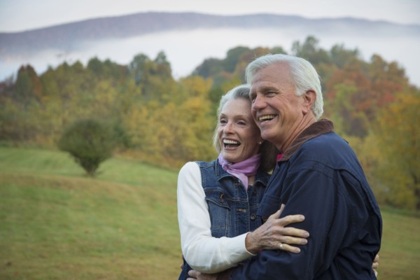 Older Caucasian couple hugging in field