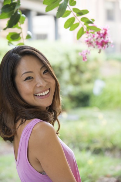 Portrait of smiling Asian woman outdoors near flowers