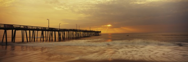 Ocean waves under pier at sunset