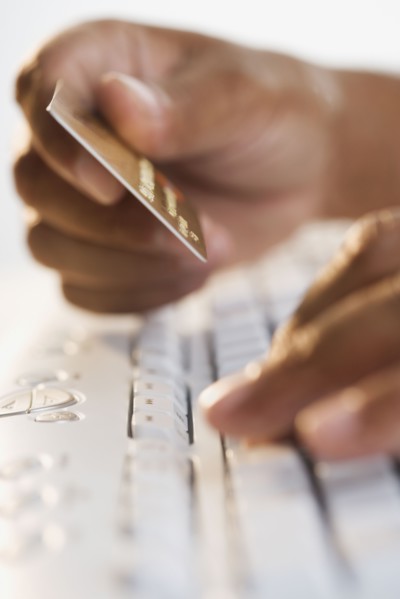 Close up of hands typing on keyboard and holding credit card