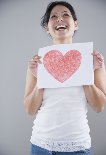 Young woman holding a piece of paper with a heart drawn on it