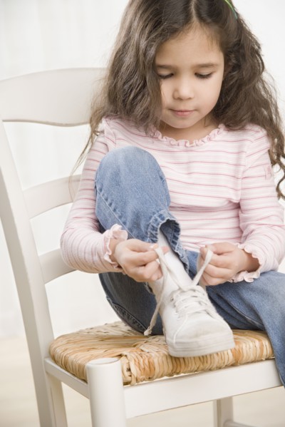 Young Hispanic girl tying shoe