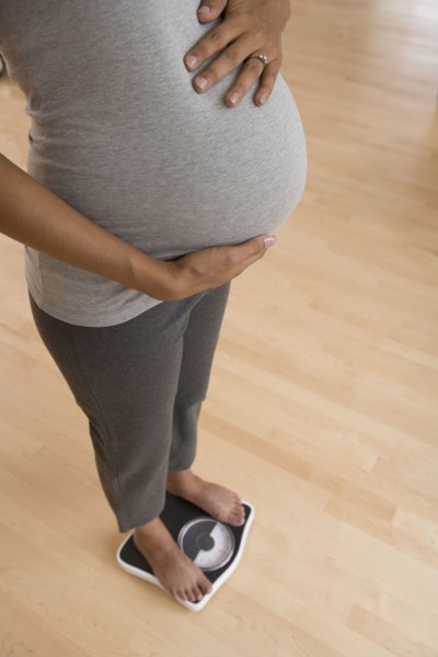 Pregnant African woman standing on scale