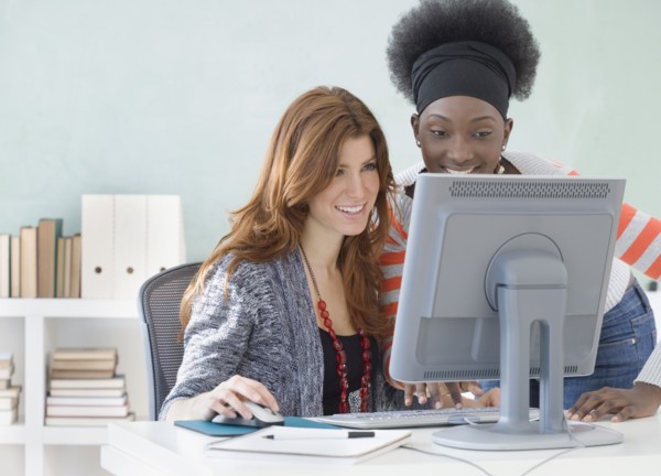 Two female college students using computer in classroom