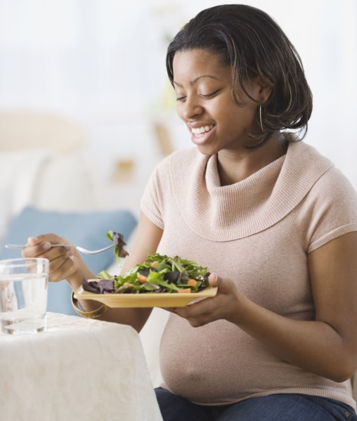 Pregnant African American woman eating salad