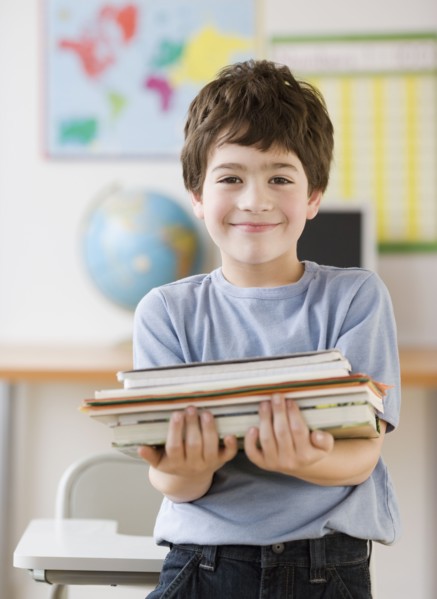 Hispanic boy holding stack of school books