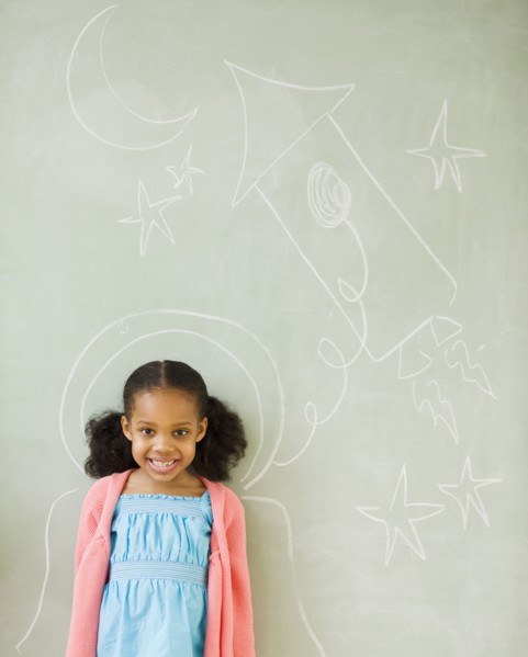 Mixed race girl standing by drawings on blackboard