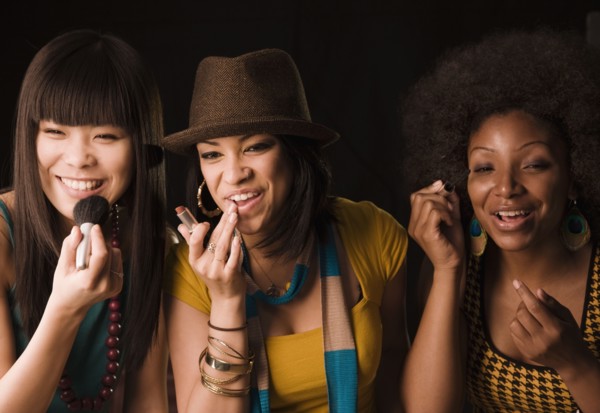 Multi-ethnic women putting on makeup