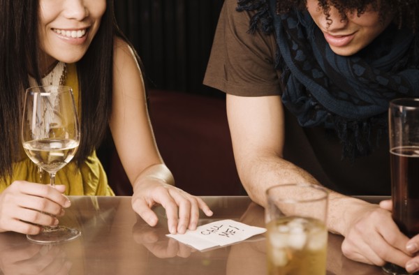 Asian woman giving mixed race man her phone number in nightclub