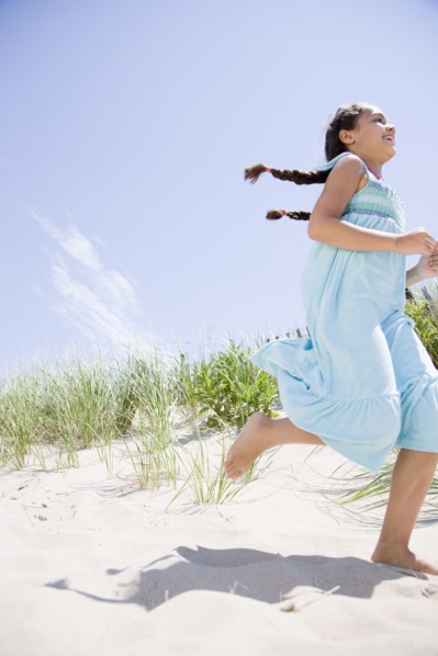 Hispanic girl running at beach