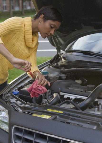 African woman checking oil in car engine