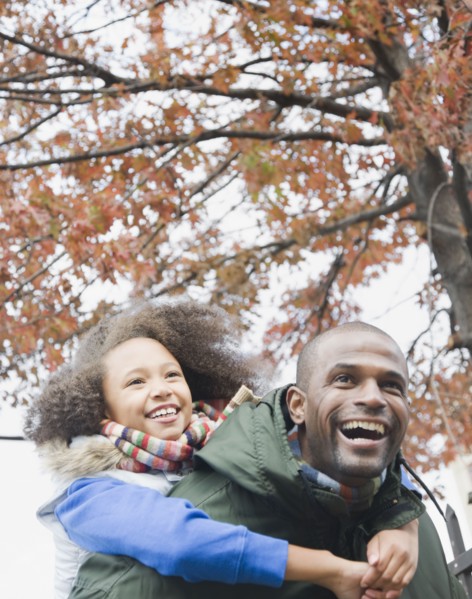 African father carrying daughter piggyback