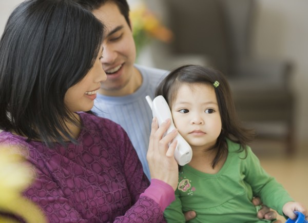 Mother and father holding telephone for daughter