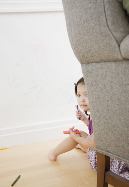 Toddler girl hiding behind chair