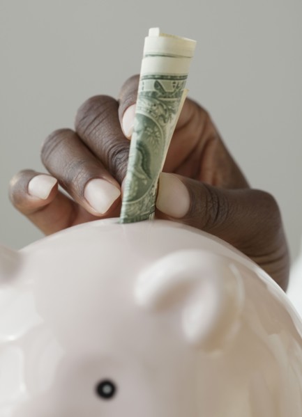 African woman putting money in piggy bank