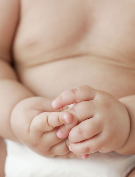 Close up of mixed race baby girl with hands clasped